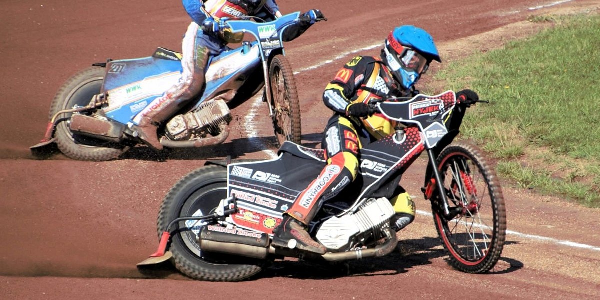 Patrick Hyjek (blauer Helm) führt Deutschland in das U19 Europafinale Zwei Speedway-Fahrer driften auf einer Sandbahn durch eine Kurve.