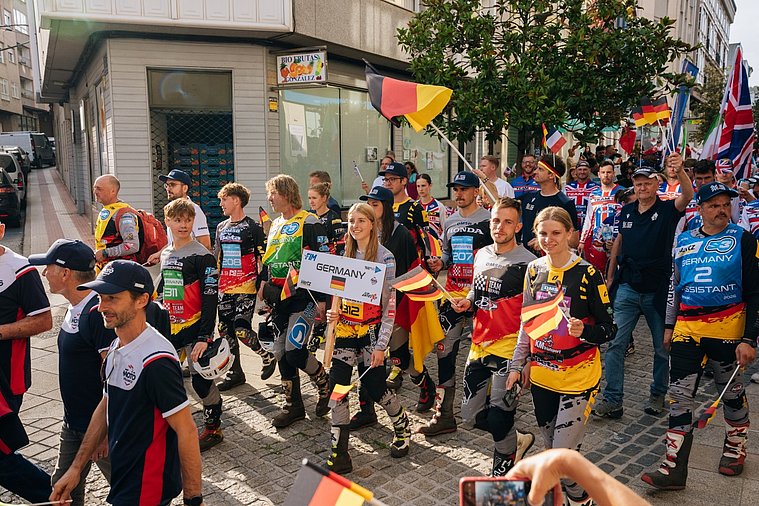 Deutsches Trial-Team zieht mit ihren Landesflaggen durch die Straßen, begleitet von Teammitgliedern und Zuschauern beim Trial der Nationen.
