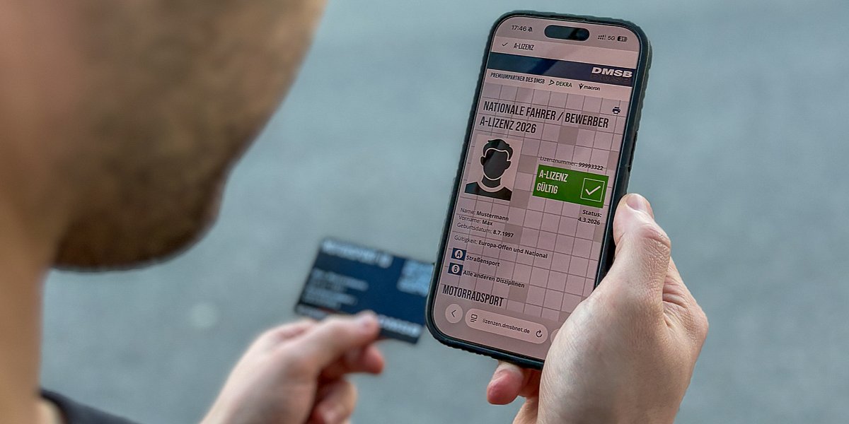 Eine Person hält ein Smartphone in der Hand, auf dem eine digitale gültige DMSB A-Lizenz 2026 zu sehen ist und hat im Hintergrund in der anderen Hand die Motorsport-ID-Checkkarte
