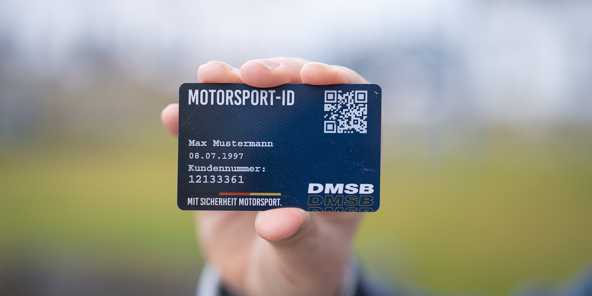 Eine Hand hält eine Motorsport-ID-Karte mit Text und einem QR-Code, der deutlich im Mittelpunkt steht.
