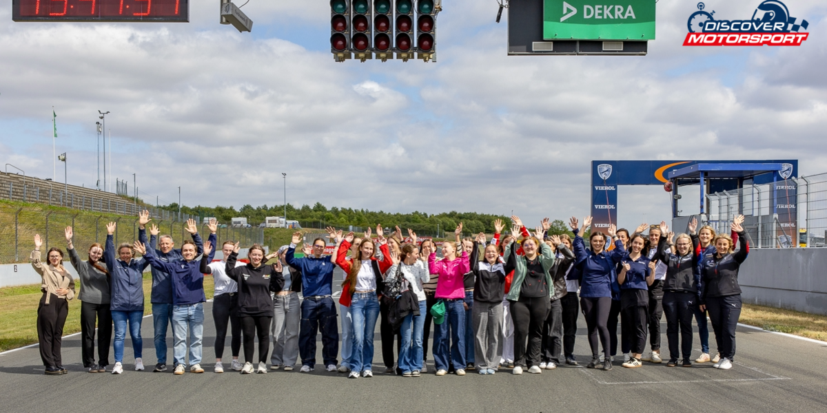 Discover Motorsport – Young Women's Edition 2026 in Oschersleben Teilnehmerinnen und Rednerinnen posieren gemeinsam für ein Gruppenfoto auf der Rennstrecke mit erhobenen Händen.