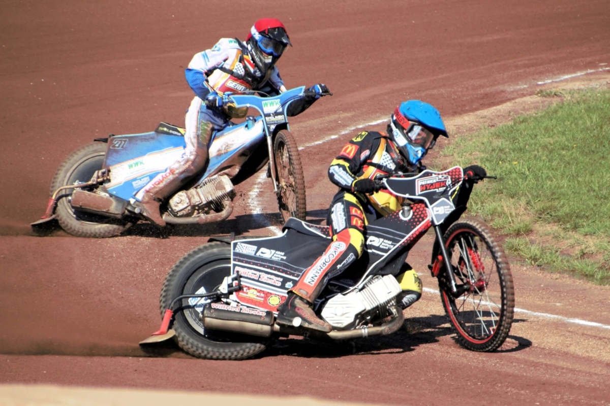 Zwei Speedway-Fahrer driften auf einer Sandbahn durch eine Kurve.