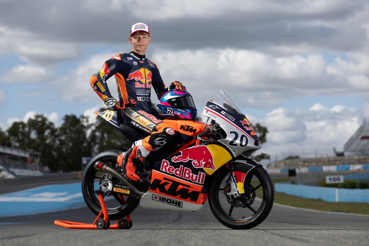 Fynn Kratochwil posiert in Rennkleidung neben seinem KTM-Rennmotorrad mit der Startnummer 20 auf einer Rennstrecke.